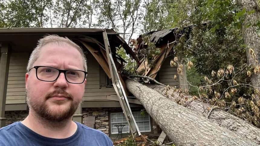 YouTuber Clint Basinger (LGR) looking into camera with hurricane-damaged home visible in background.