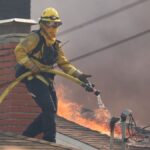 A cropped Cal Fire photo of a firefighter on a rooftop during the 2025 Palisades Fire.