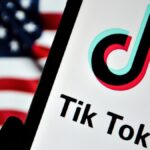 A phone displaying the TikTok logo in front of the US flag.