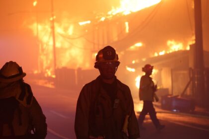 Firefighters in front of a burning structure during the 2025 Palisades Fire in LA County.