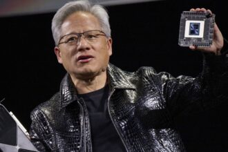 Jensen Huang, co-founder and chief executive officer of Nvidia Corp., speaks while holding the company's new GeForce RTX 50 series graphics cards and a Thor Blackwell robotics processor during the 2025 CES event in Las Vegas, Nevada, US, on Monday, Jan. 6, 2025. Huang announced a raft of new chips, software and services, aiming to stay at the forefront of artificial intelligence computing. Photographer: Bridget Bennett/Bloomberg via Getty Images