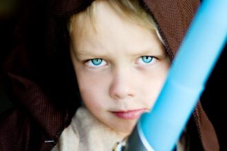 A child poses with a toy lightsabre.