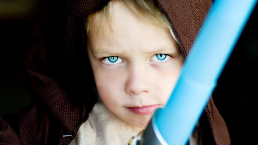 A child poses with a toy lightsabre.