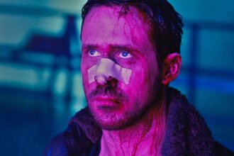 Ryan Gosling looking worse for wear looking up lit by purple light