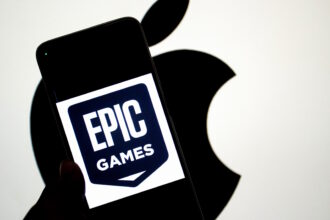 INDIA - 2024/09/14: In this photo illustration, an Epic Games logo seen displayed on a smartphone with an Apple logo in the background. The relationship between Epic Games and Apple became widely known due to a legal dispute. In 2020, Epic Games, the creator of the popular game Fortnite, challenged Apple's App Store policies by introducing a direct payment option in Fortnite, bypassing Apple's 30% commission on in-app purchases. Apple responded by removing Fortnite from the App Store, leading to a major lawsuit. Epic accused Apple of anti-competitive behavior, claiming that the company had a monopoly on app distribution and payments within its ecosystem. The case, which addressed broader issues of app store policies and digital marketplaces, attracted significant attention and sparked debate about the control tech giants have over their platforms. (Photo Illustration by Avishek Das/SOPA Images/LightRocket via Getty Images)